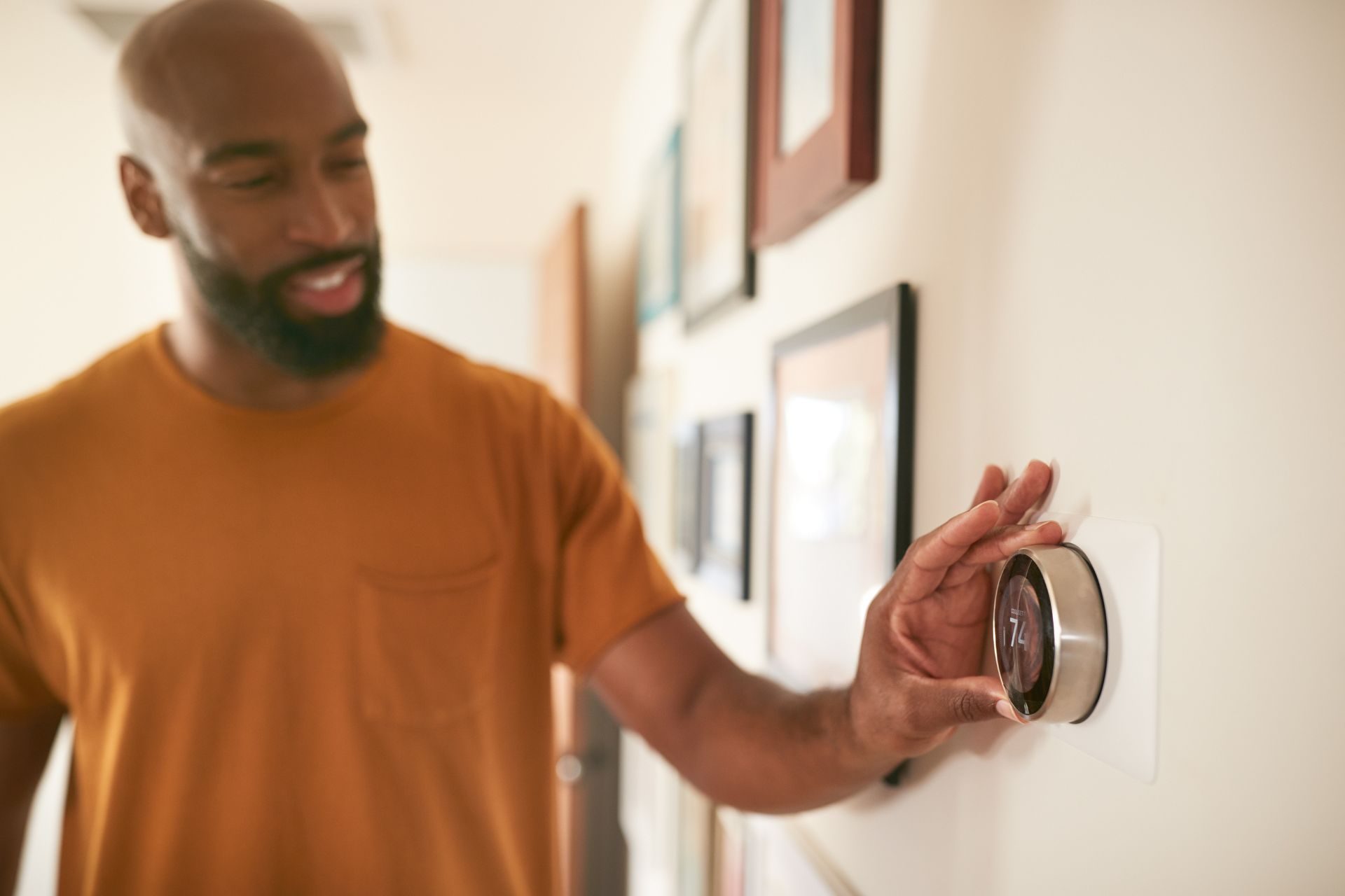 A man adjusts his digital smart thermostat