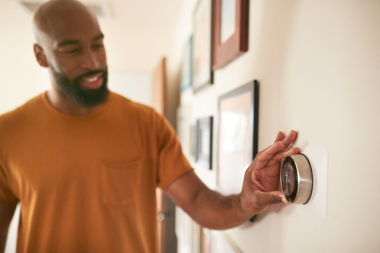 A man adjusts his digital smart thermostat